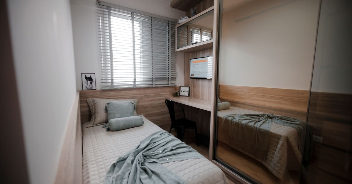 Compact ship cabin interior with a small bed, wood panels and a round porthole