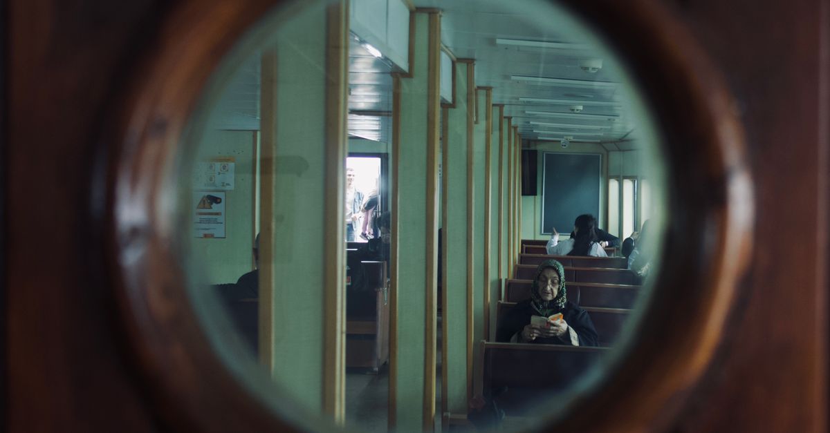 Interior compacto de camarote de barco con una cama pequeña, paneles de madera y un ojo de buey redondo
