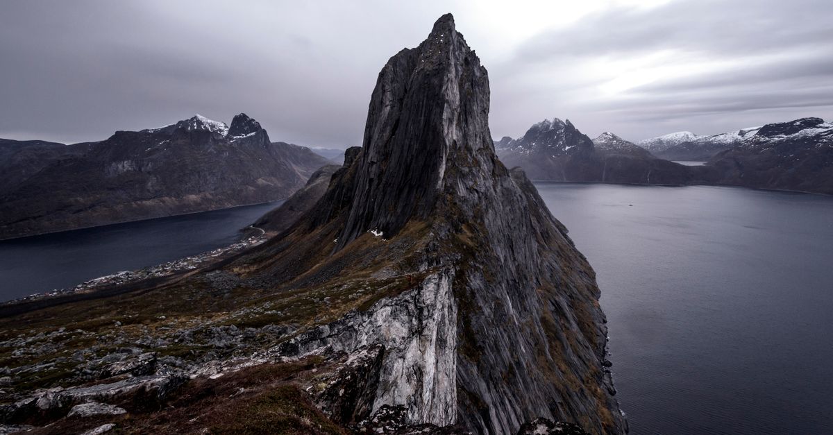 Narrow fjord channel with steep rock walls and calm water under soft daylight