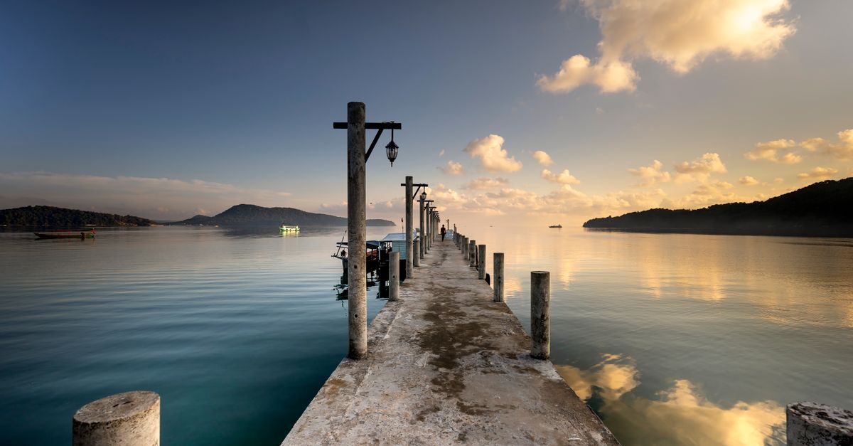 Gangway ramp leading from a stone pier toward a small moored ship